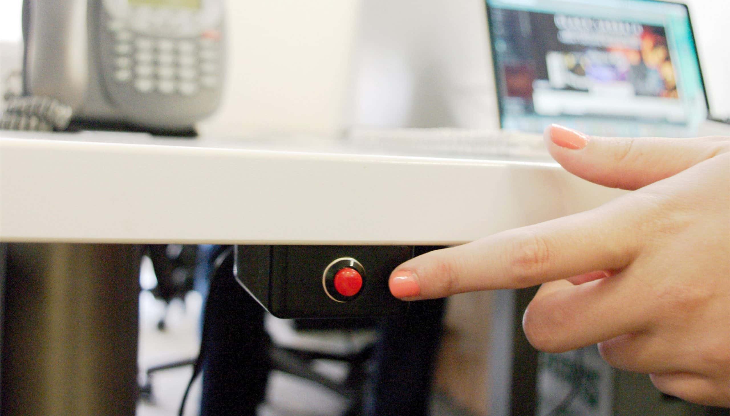 Hand approaching panic button under desk