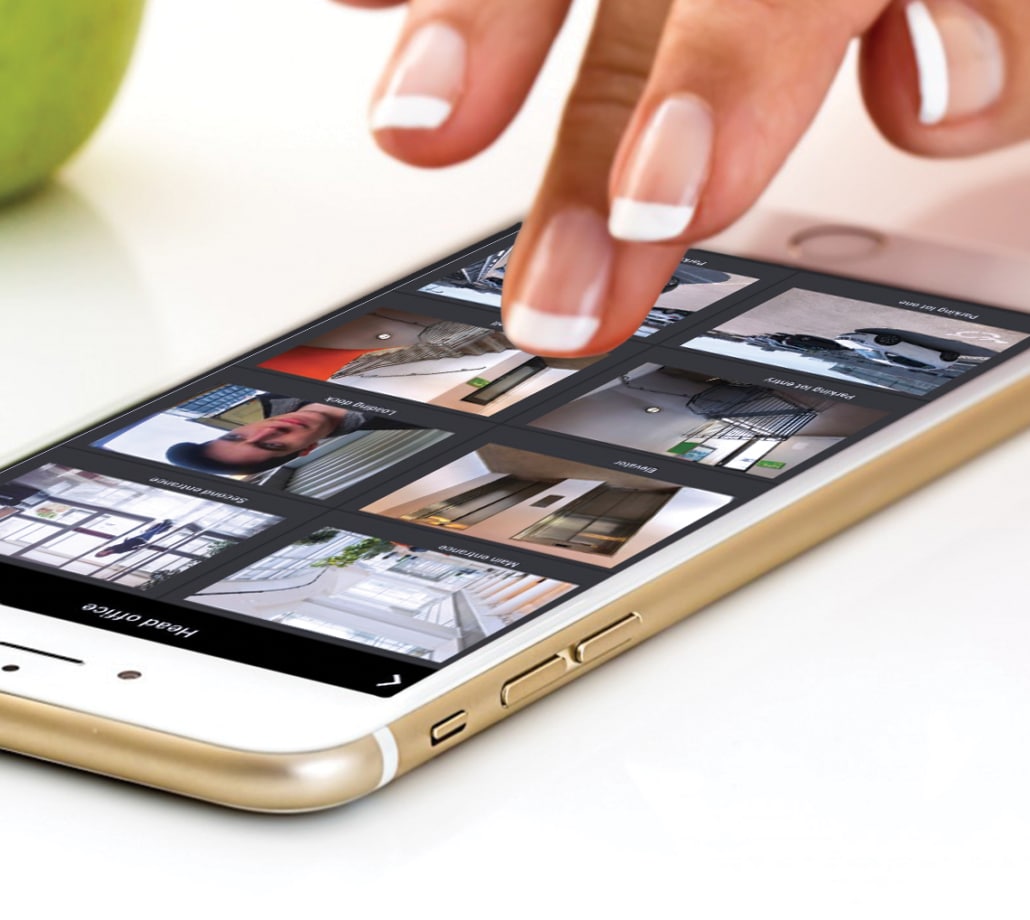 Human hand hovering above mobile phone that displays surveillance feeds